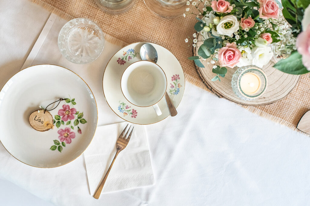Tischgedeck mit Geschirr, Blumen und Kerzen. Tischdecke und Juteläufer. Feierlich eingedeckt in mittelfrankens schönstem Eventstadl.