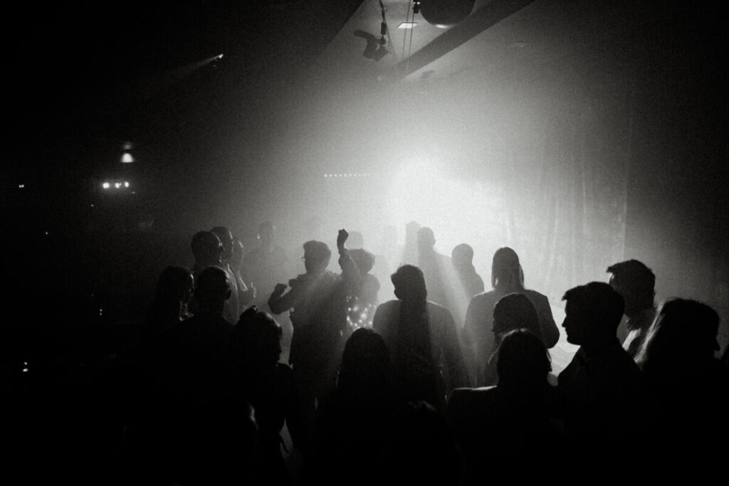 Afterparty in der Disco, Gäste feiern auf der Tanzfläche im Disconebel mit Discobeleuchtung