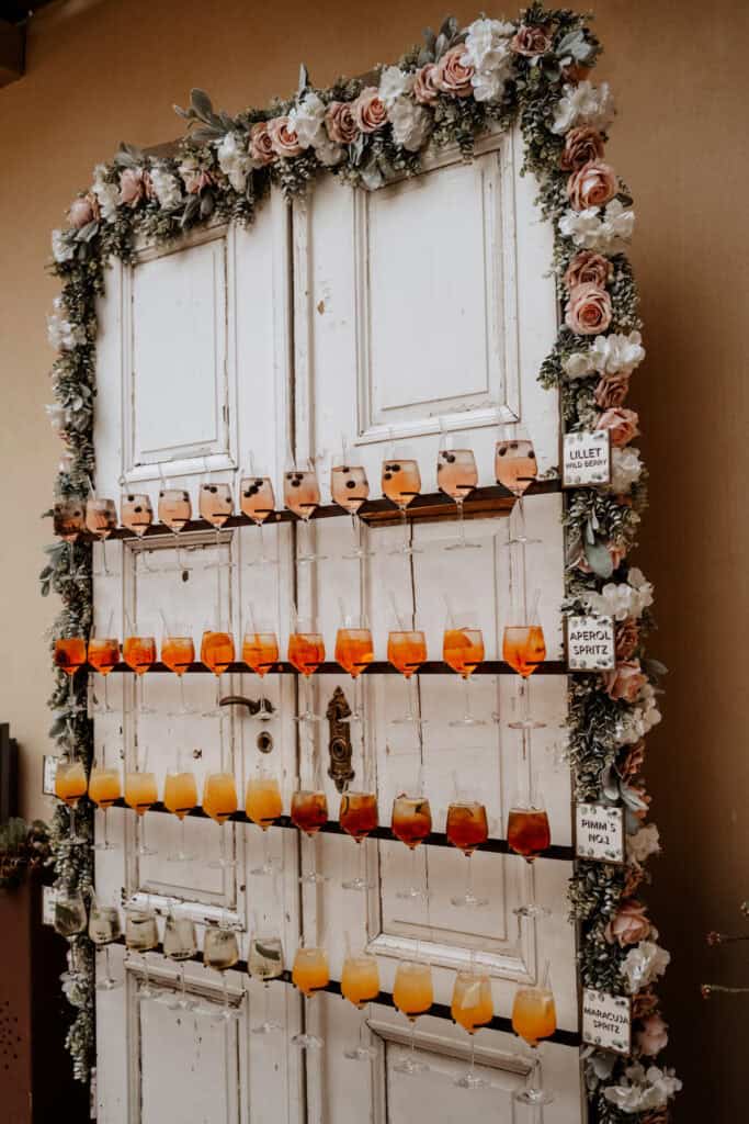 Antike Schlosstür mit Blumen verzweit, an der Schlosstür hängen vorbereitete Aperitive in verschiedenen Variationen. Zur selbstbedienung für die Gäste der Hochzeit.