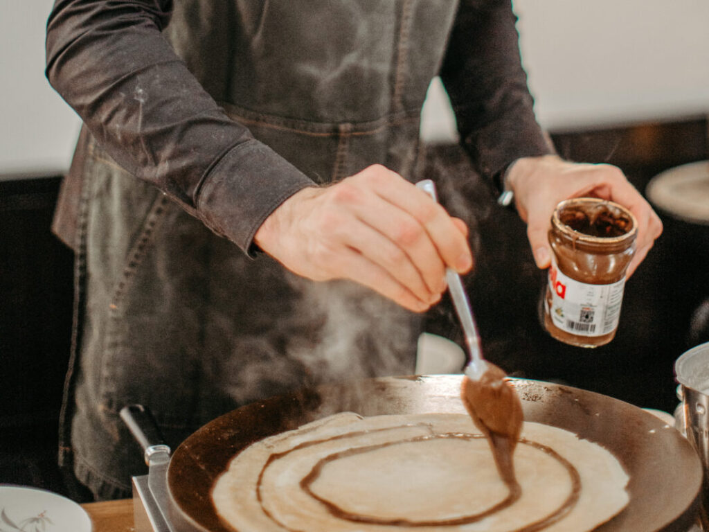 Frische Crepes am Dessertbuffet, Nutella & Banane wir von einem Mitarbeiter am Buffet angerichtet.