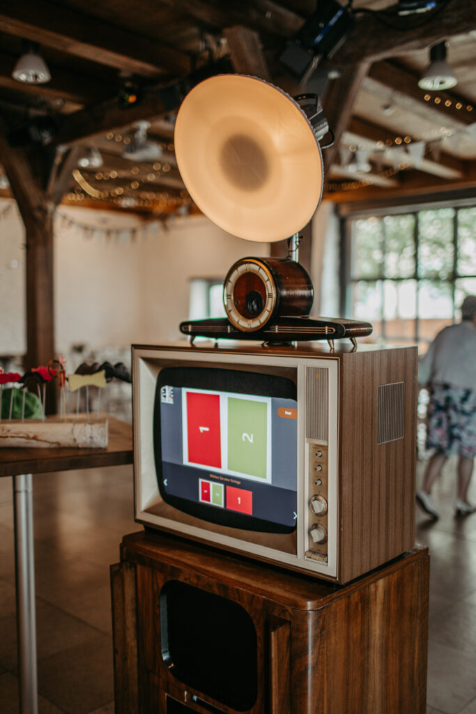 Fotobox im Vintage-Style mit Röhrenfernsehr und Uhr als Kameragehäuse, Fotoblitz und Fotodrucker. Fotobox im Spitalstadl Hochzeitssaal in Freystadt.