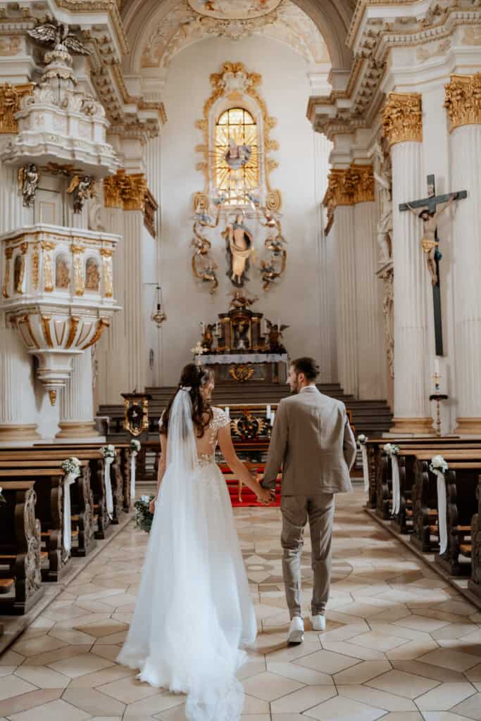 Brautpaar in der Wallfahrtskirche in Freystadt in der Oberpfalz, Hand in Hand vor dem Traualtar in der katholischen Wallfahrtskirche.