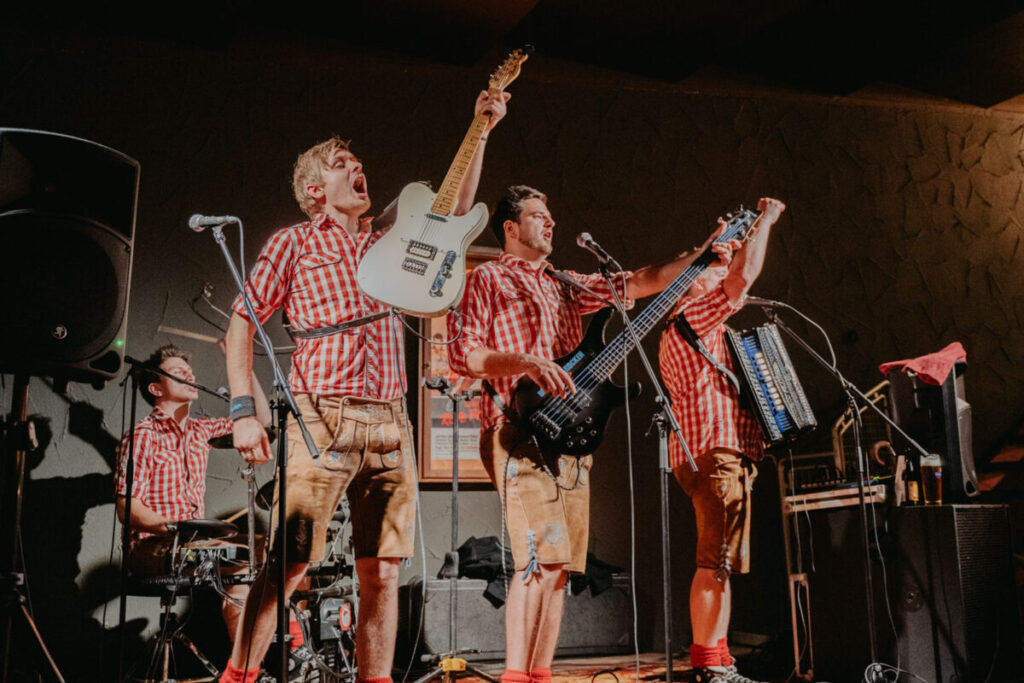 Brautentführung im Discosaal bei einer Hochzeit im SPitalstadl, die Band steht auf der Bühne und spielt Musik, der Gitarrist mit einer euphorischen Geste streckt seine Gitarre in die Luft und jubelt.