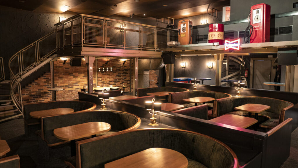 Der Kinosaal und Discosaal im Cafe Beck, mit Sitzgruppen und warmer Beleuchtung. Im Hintergrund eine Empore und Dekoration.